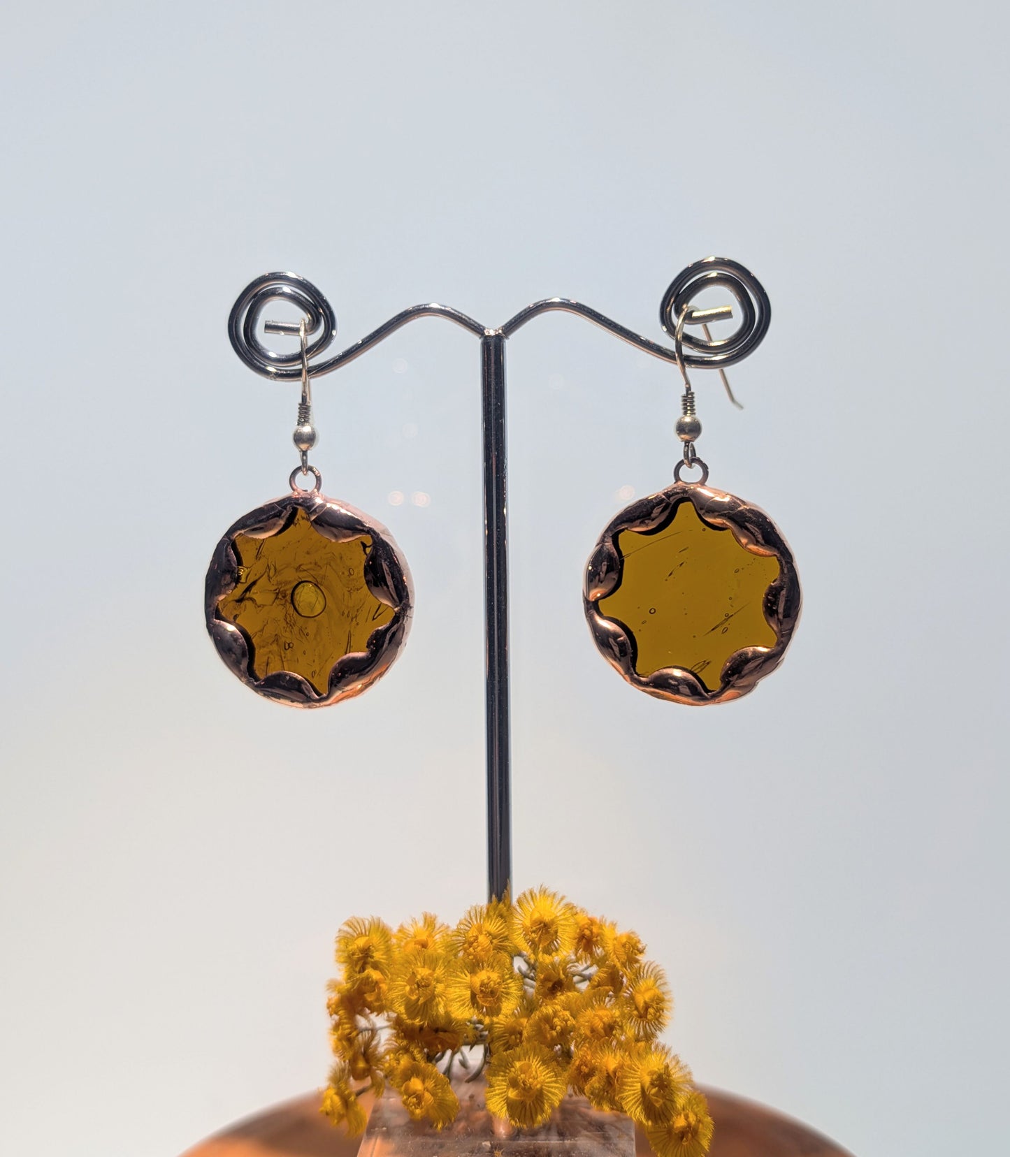 Pair of round earrings on a stand with a light background