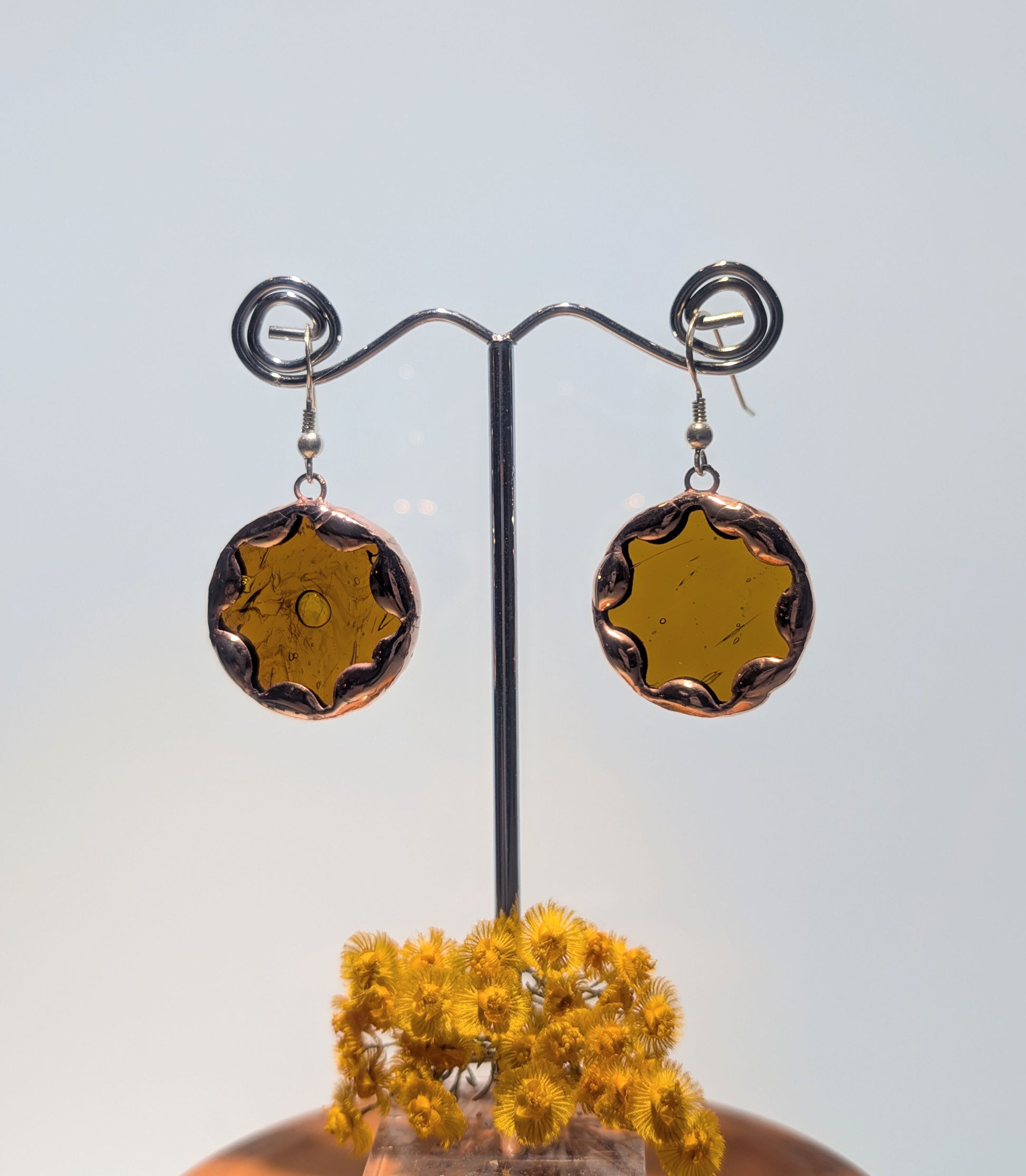 Pair of round earrings on a stand with a light background