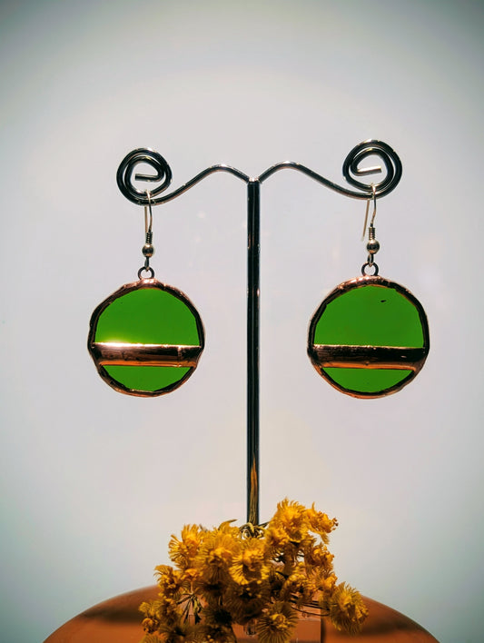 Green circular earrings on a stand with a blurred background