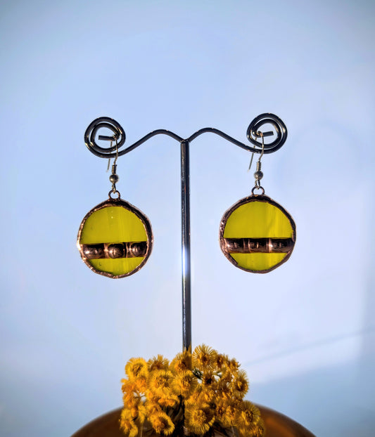 Yellow earrings on a metal stand with a blue background