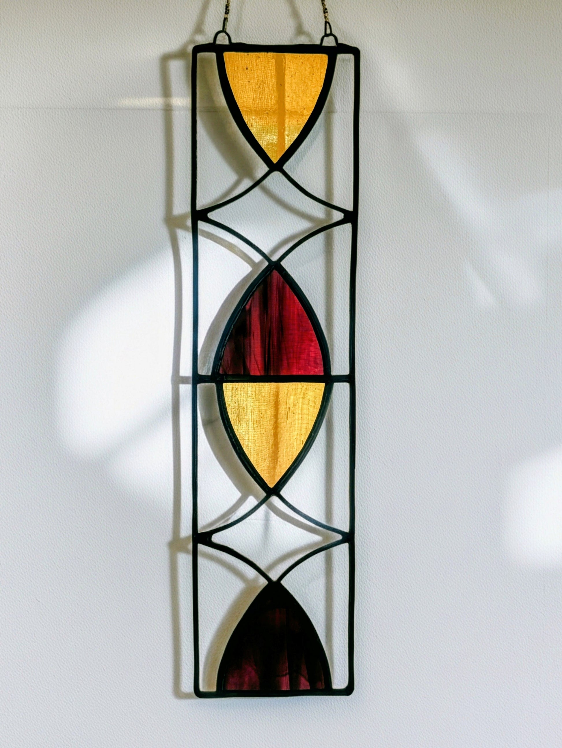Stained glass panel with geometric design on a white wall