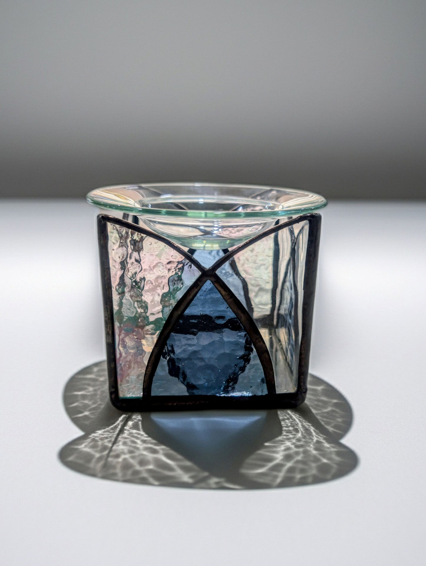 Glass candle holder with decorative metal base on a gray background
