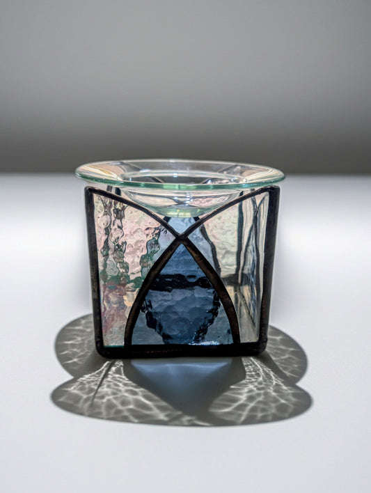 Glass candle holder with decorative metal base on a gray background