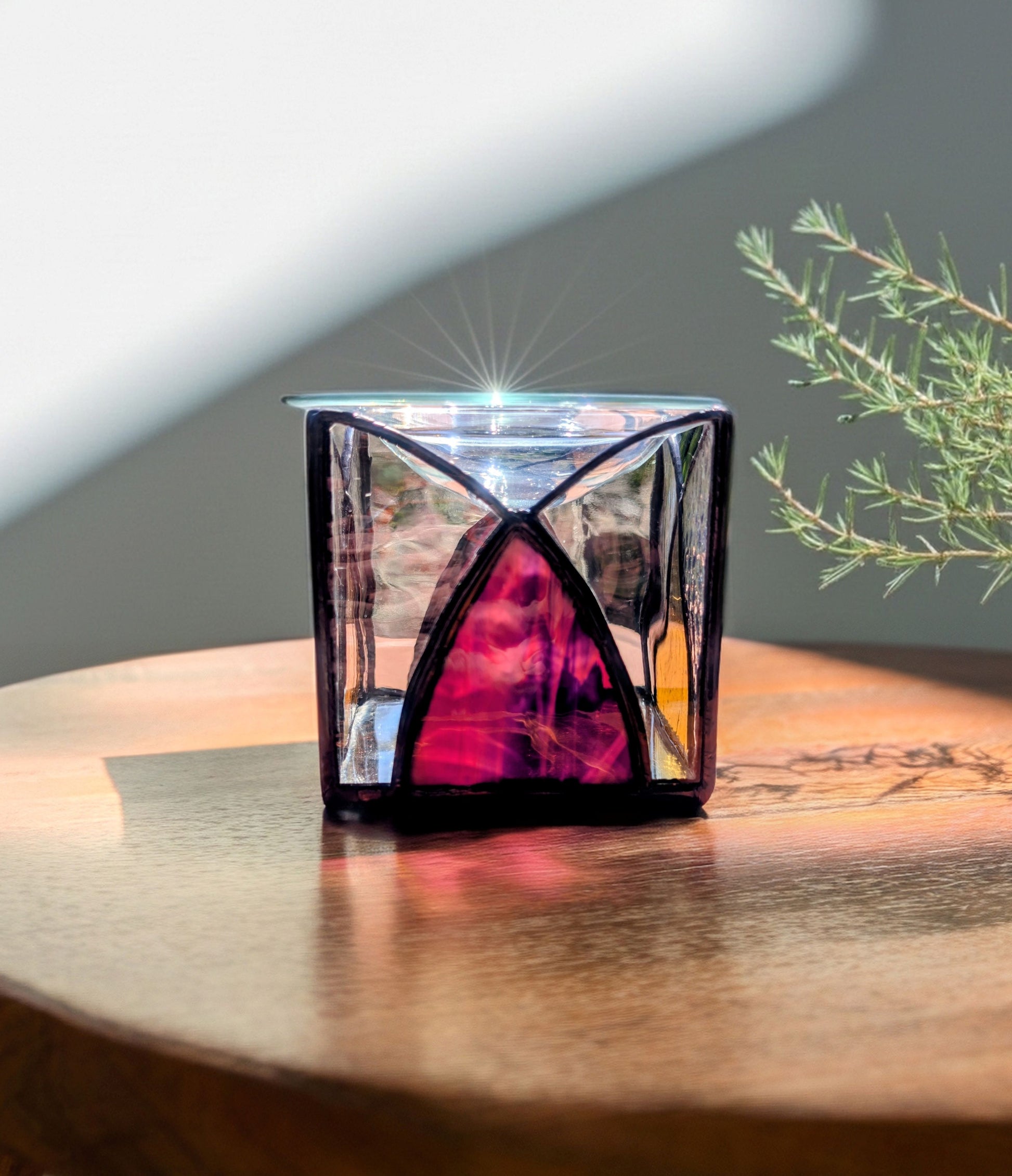Glass candle holder with a red interior on a wooden surface