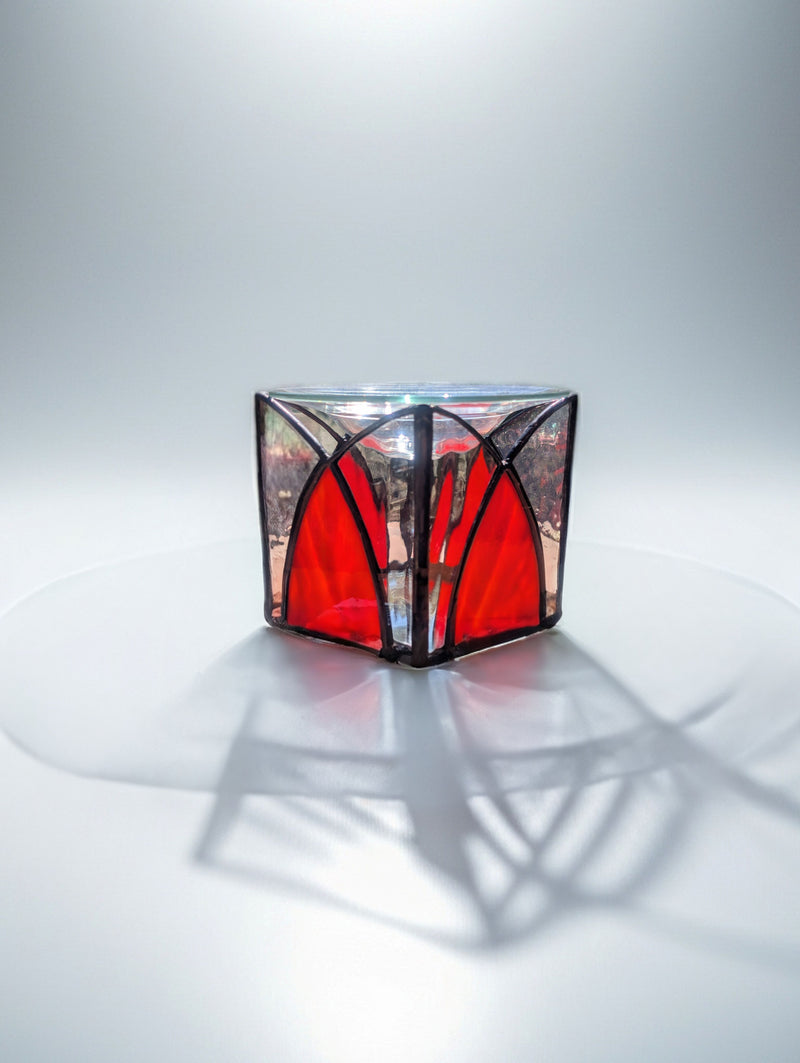 Stained glass cube with red and black design on a white background